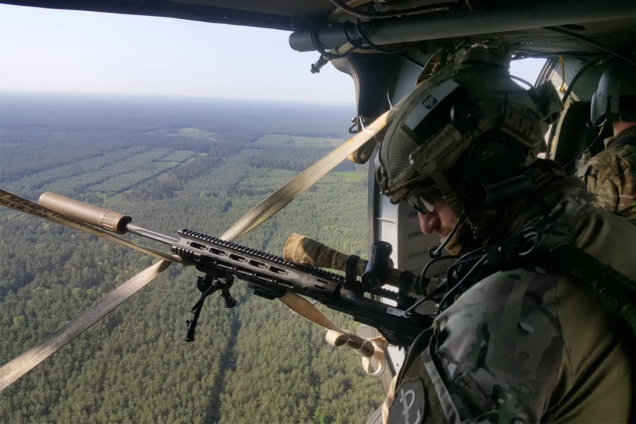 Sniper conducting overwatch from helicopter